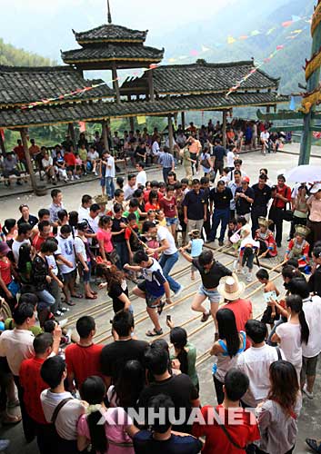 10月5日,在广西融水苗族自治县沟滩苗寨,游客学跳苗族竹竿舞。国庆长假期间,广西融水县各旅游景点推出了具有浓郁民族特色的传统民俗节目。