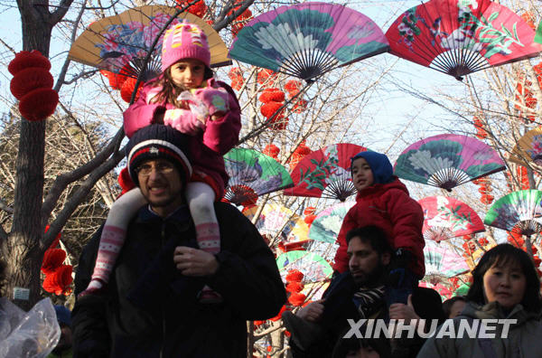 1月25日,两位外国游客驮着孩子逛地坛庙会,感受中国春节民俗文化.