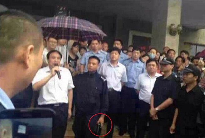 河南县官与民众对话：警察持枪撑伞护卫画面