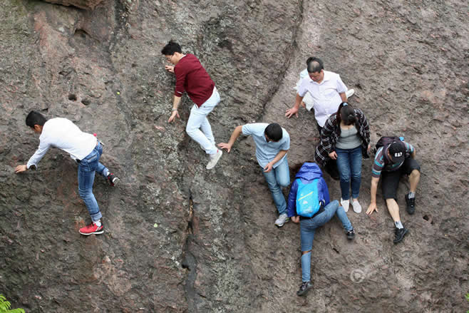 杭州一景区人潮拥挤 游客冒险爬崖抄近道