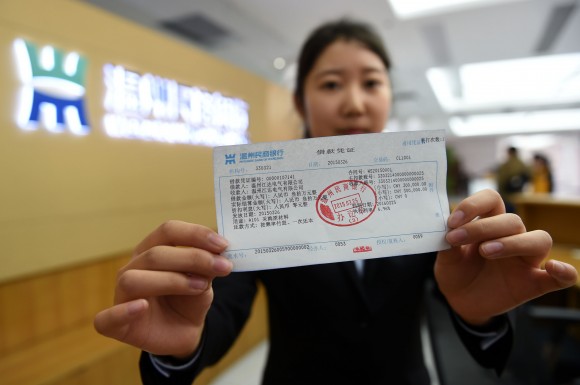 工作人员展示温州民商银行办理的第一笔贷款凭证