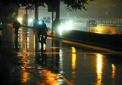 6月16日中午,市民在北京广安门大街冒雨骑行,周边路灯全部点亮,宛如