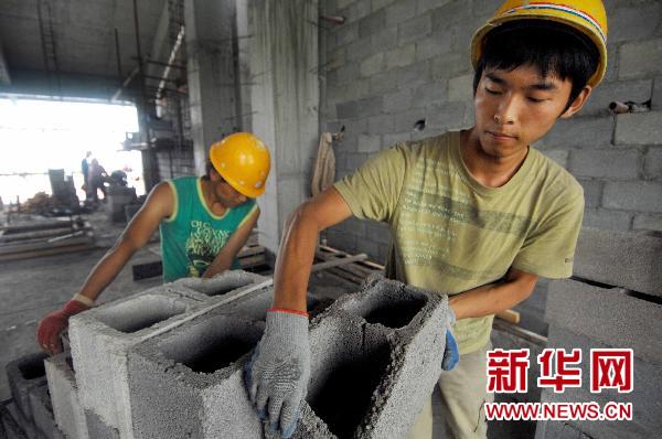 8月9日,在学校工地上打工的大学生在搬运空心砖.