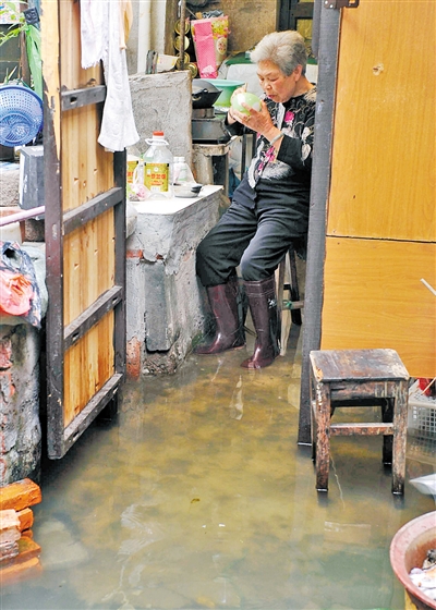 80歲的李阿香老人家中進水,只能穿著雨靴在水中吃飯.